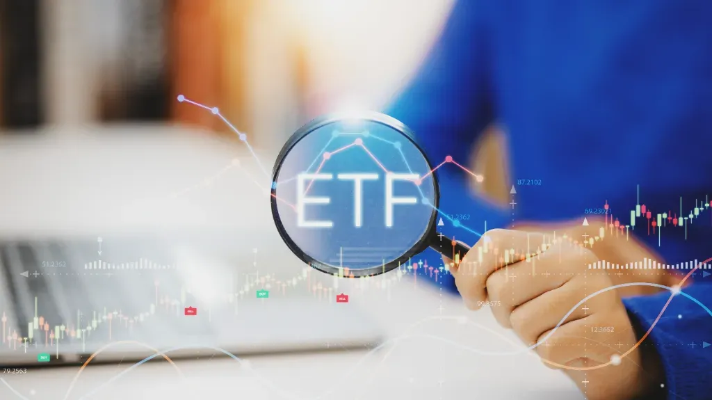ETF: rynki rozwinięte i rynki wschodzące po lupą trzymaną przez mężczyznę siedzącego przed laptopem